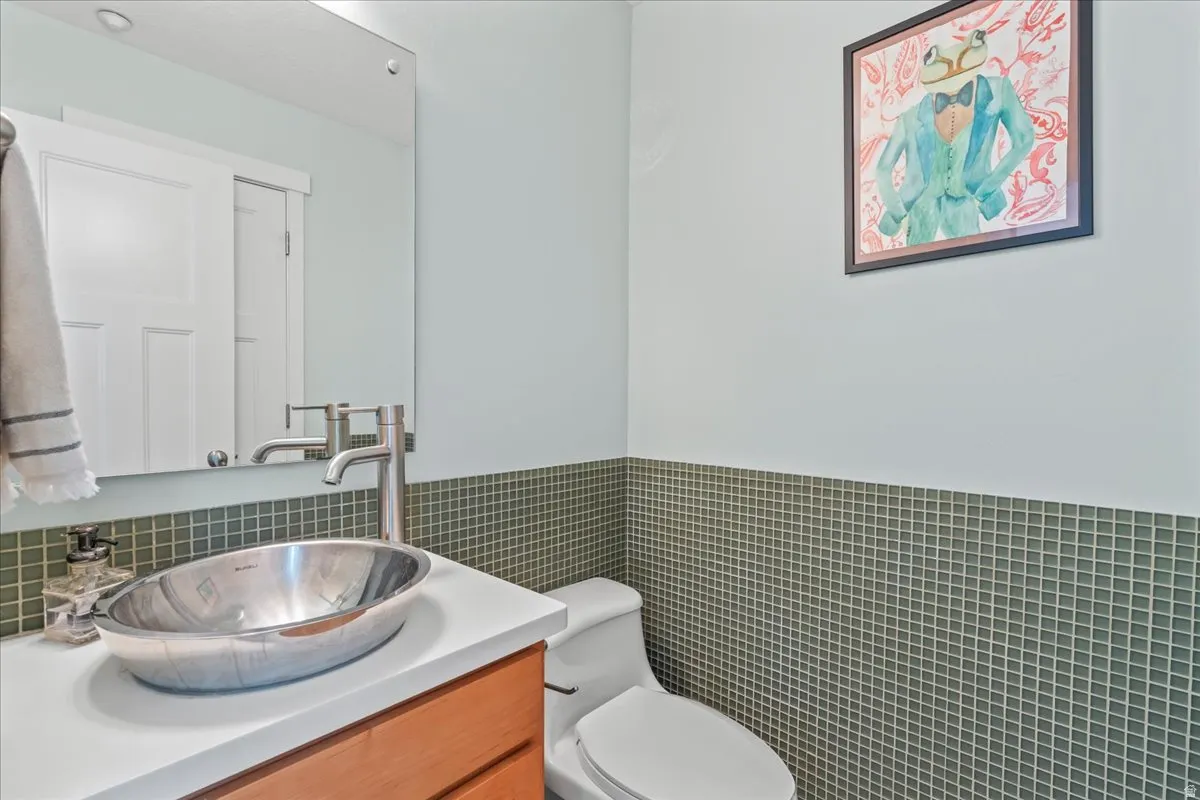 Modern powder room with a vessel sink, single-hole faucet, white countertop, and wood-finish cabinetry