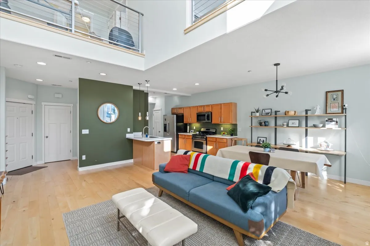Open-concept living area featuring light wood-finish flooring, a kitchen with wood cabinetry and stainless steel appliances, and a dining space with built-in shelving