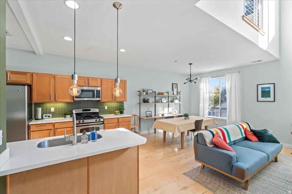 Open-concept living space featuring high ceilings, wood-finish flooring, and a kitchen island with an undermount sink