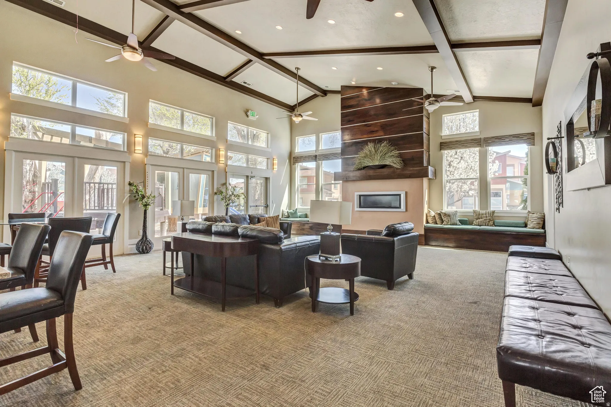 Vaulted ceiling with exposed beams, multiple ceiling fans, and abundant natural light from numerous windows