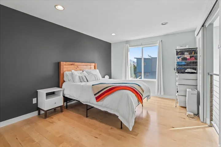 Bright room featuring recessed lighting, a large window, light-toned wood-finish flooring, and a sliding door with a metal railing