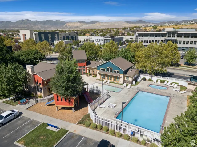 Community amenity area featuring a large swimming pool, two hot tubs, and a dedicated play structure