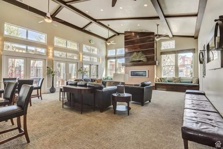 Vaulted ceiling with exposed beams, multiple ceiling fans, and abundant natural light from numerous windows