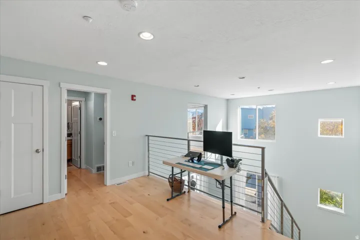 Bright open landing featuring light wood-finish flooring, recessed lighting, and a modern cable railing system