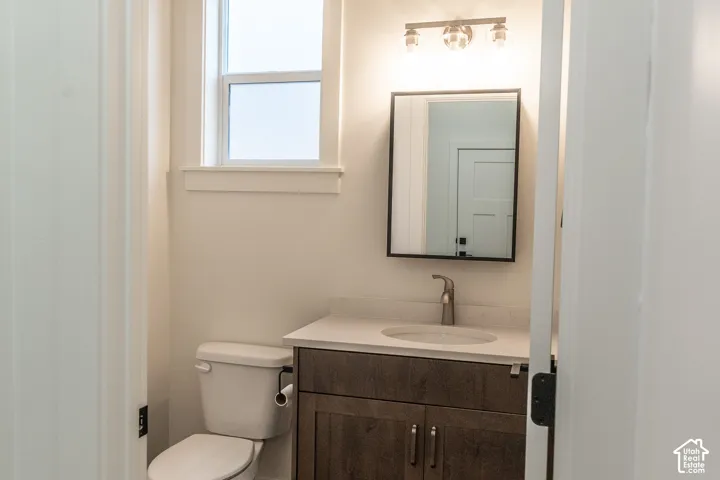 Single-handle faucet, oval undermount sink, wood-finish vanity with panel doors, wall-mounted mirror, and a window with white trim