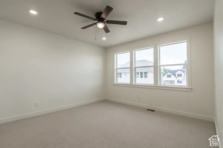 Recessed lighting, ceiling fan with integrated light, triple window assembly, neutral carpeting, and light wall finishes