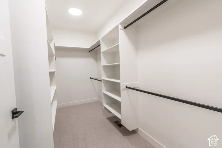 Walk-in closet featuring white built-in shelving, black hanging rods, and recessed lighting