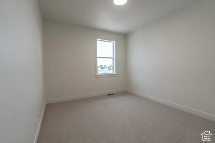 Neutral-toned carpeting paired with white walls, a single window, and a flush-mount ceiling light