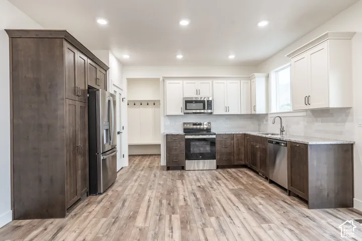 Kitchen featuring wood-finish flooring, two-tone cabinetry, stainless steel appliances, and recessed lighting