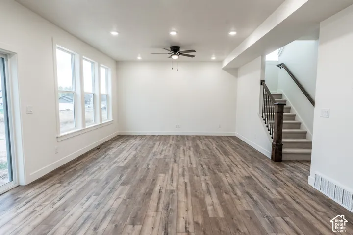 Spacious room featuring wood-finish flooring, recessed lighting, and a ceiling fan
