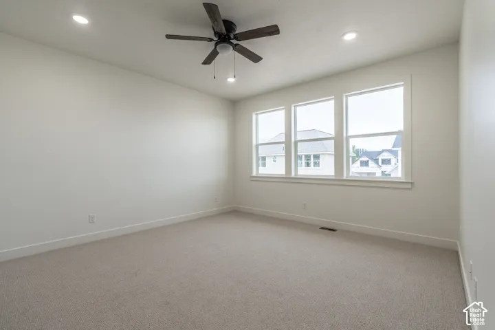 Spacious room with plush carpeting, three large windows, a ceiling fan, and recessed lighting