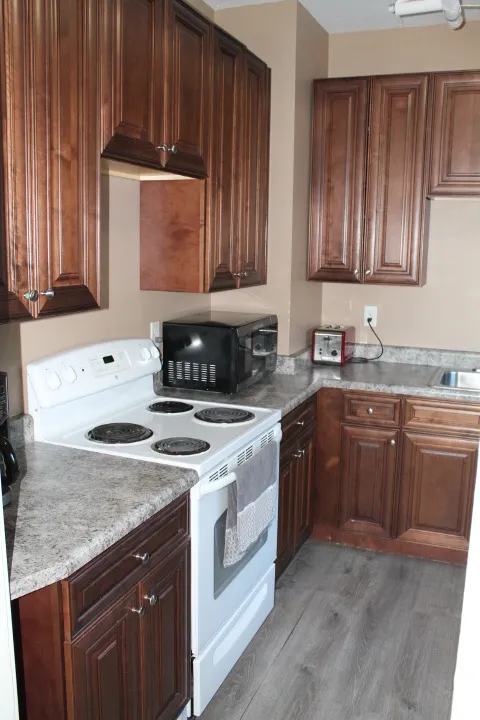 Kitchen featuring wood-finish cabinetry, speckled countertops, and wood-finish flooring