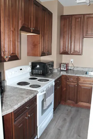 Kitchen featuring wood-finish cabinetry, speckled countertops, and wood-finish flooring