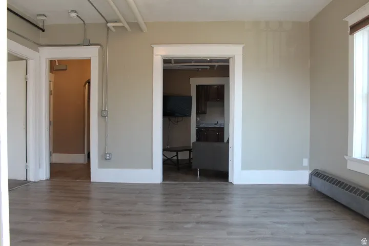 Spacious room featuring wood-finish flooring, neutral paint palette, and ample natural light from a window