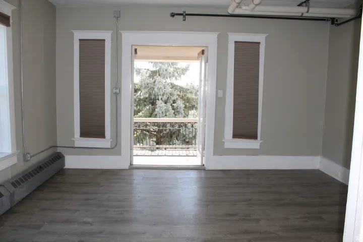 Room featuring wood-finish flooring, light grey painted walls, and white trim