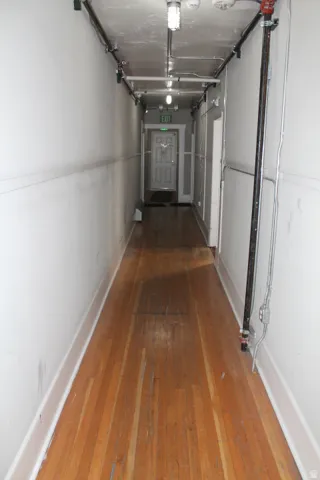 Hardwood flooring extending through a white-walled corridor
