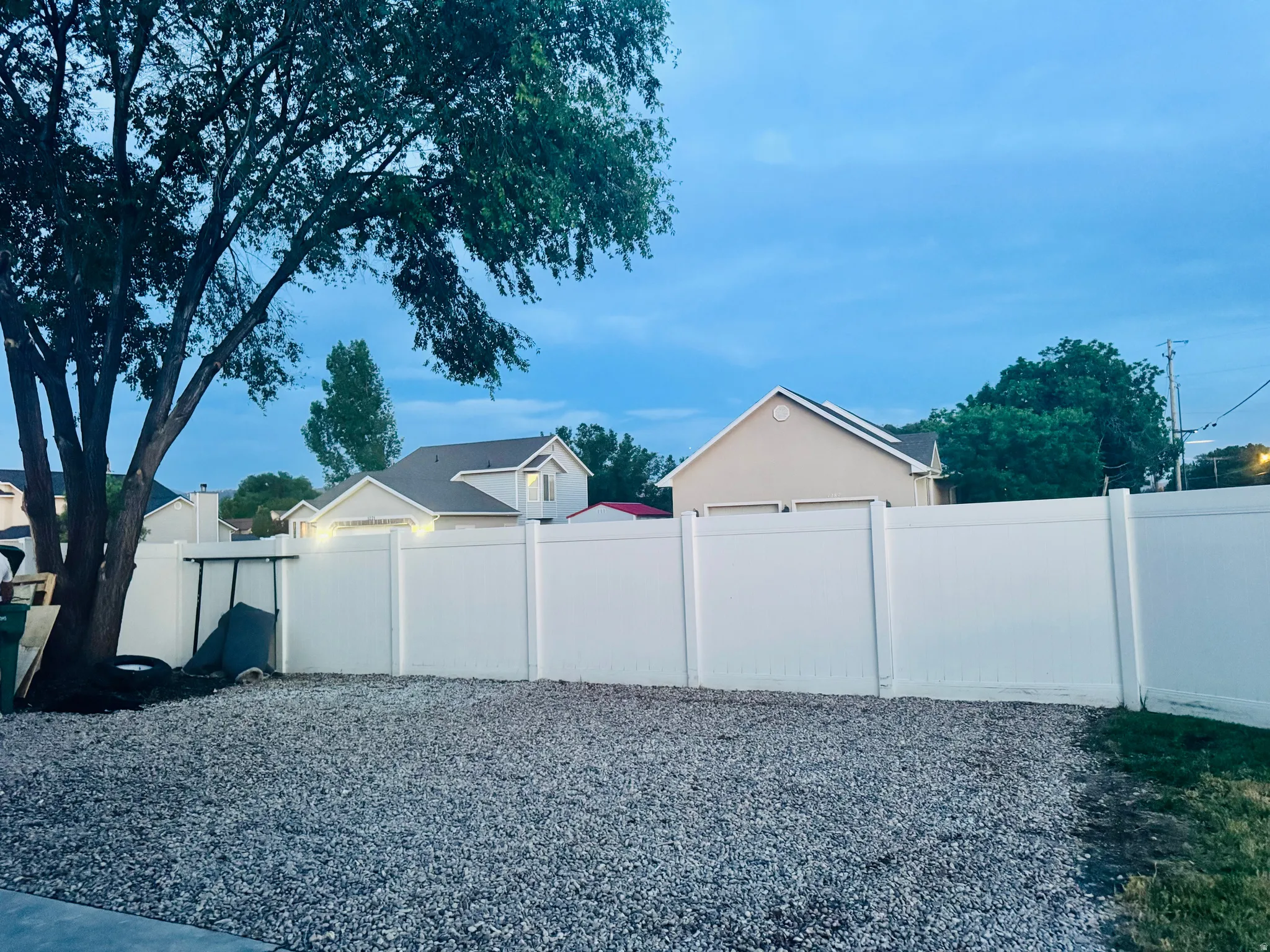 Gravel-covered outdoor space with a white privacy fence