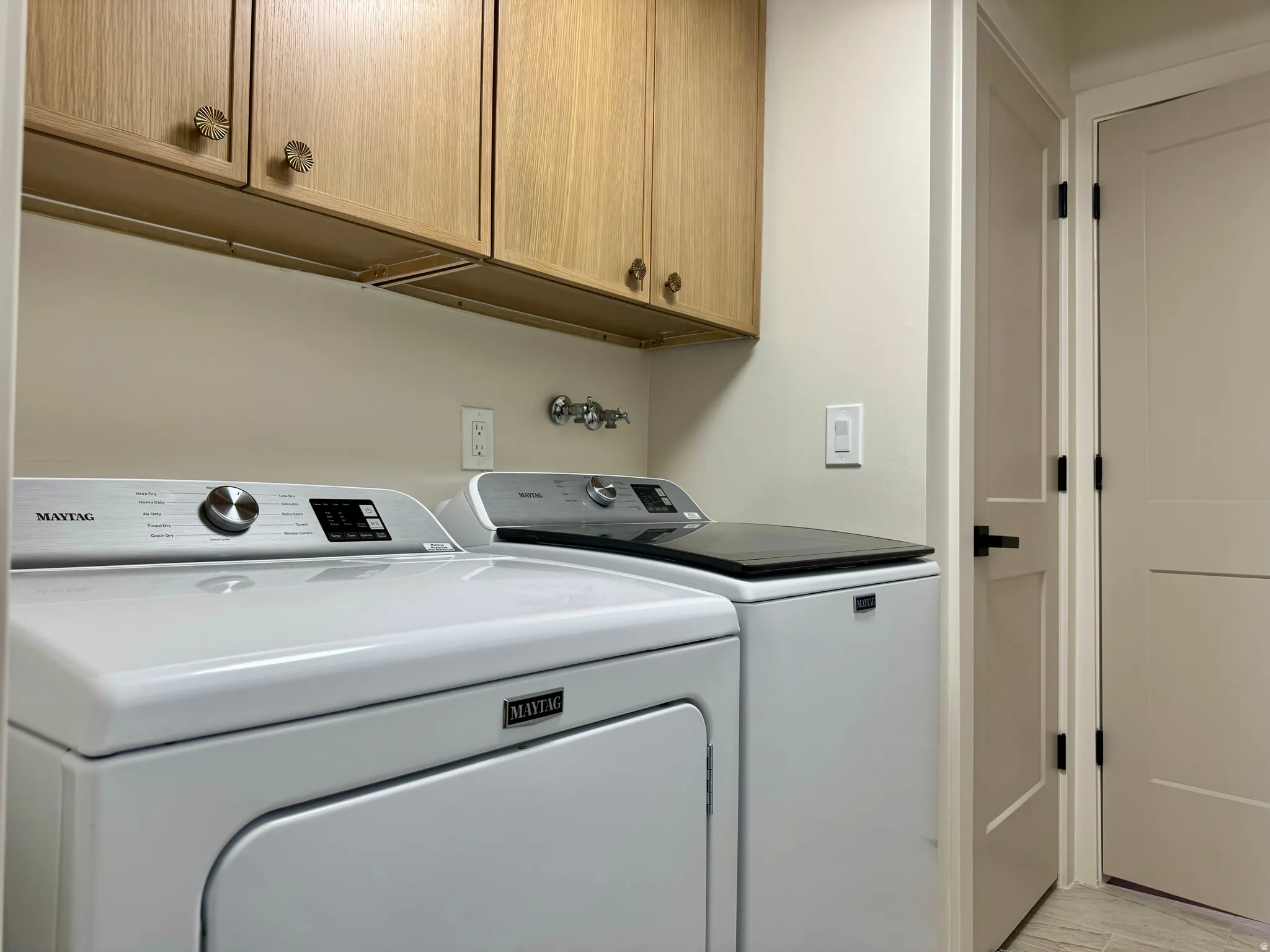 Laundry area featuring upper wood cabinetry with decorative knobs