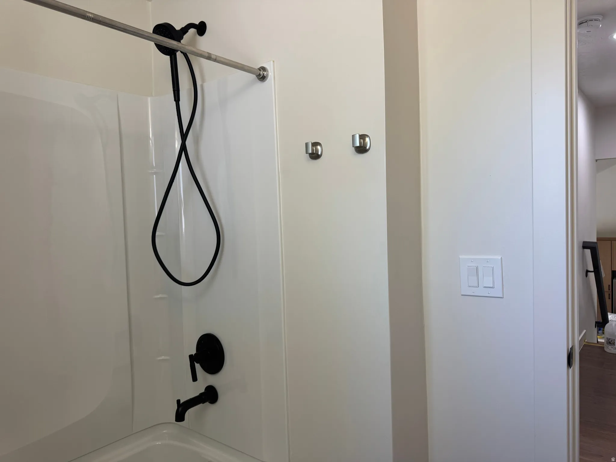 Tub and shower combination featuring a white surround, matte black fixtures, and a curved shower rod
