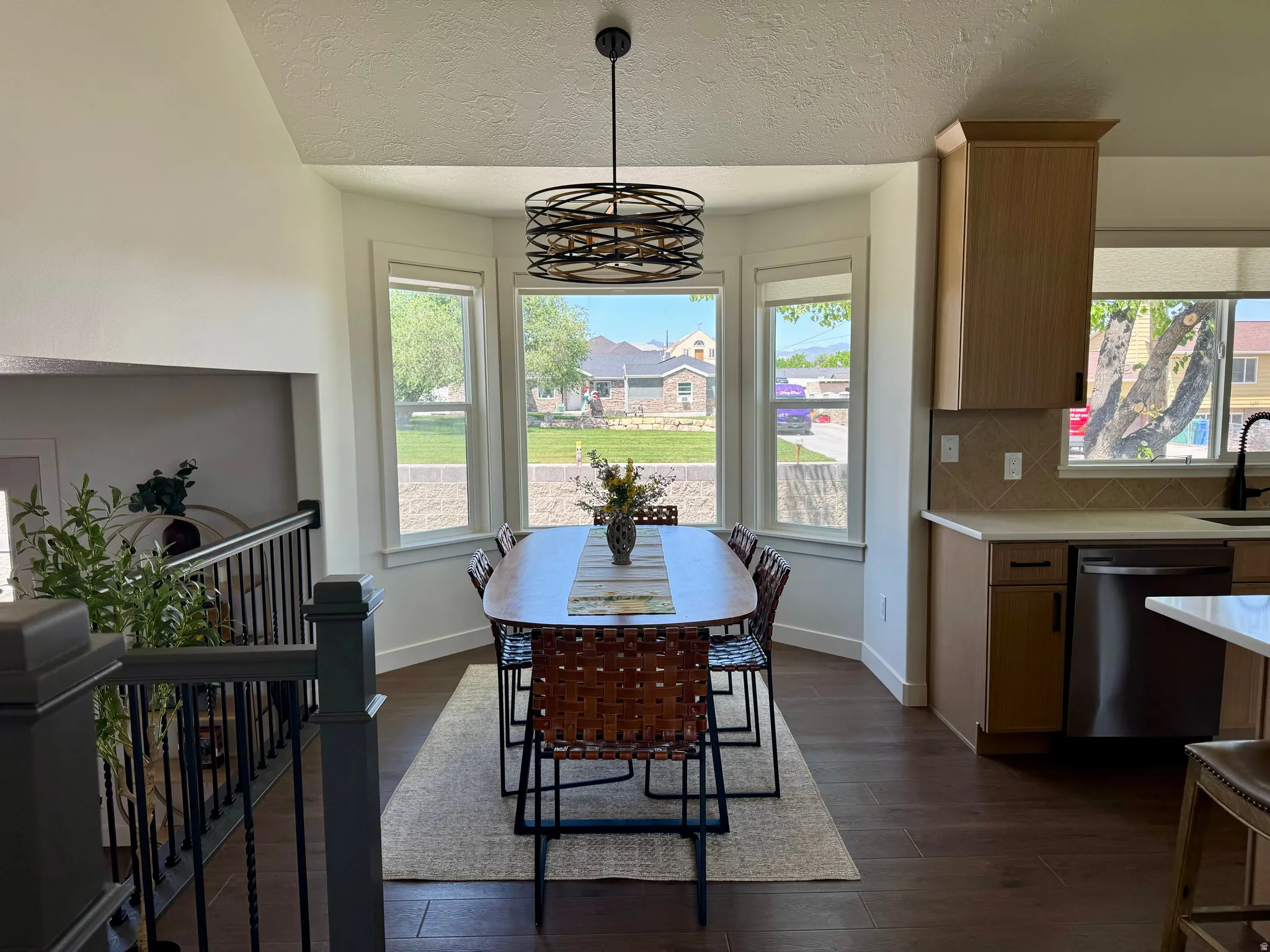 Dining area with a sophisticated circular pendant light fixture and a bay window configuration