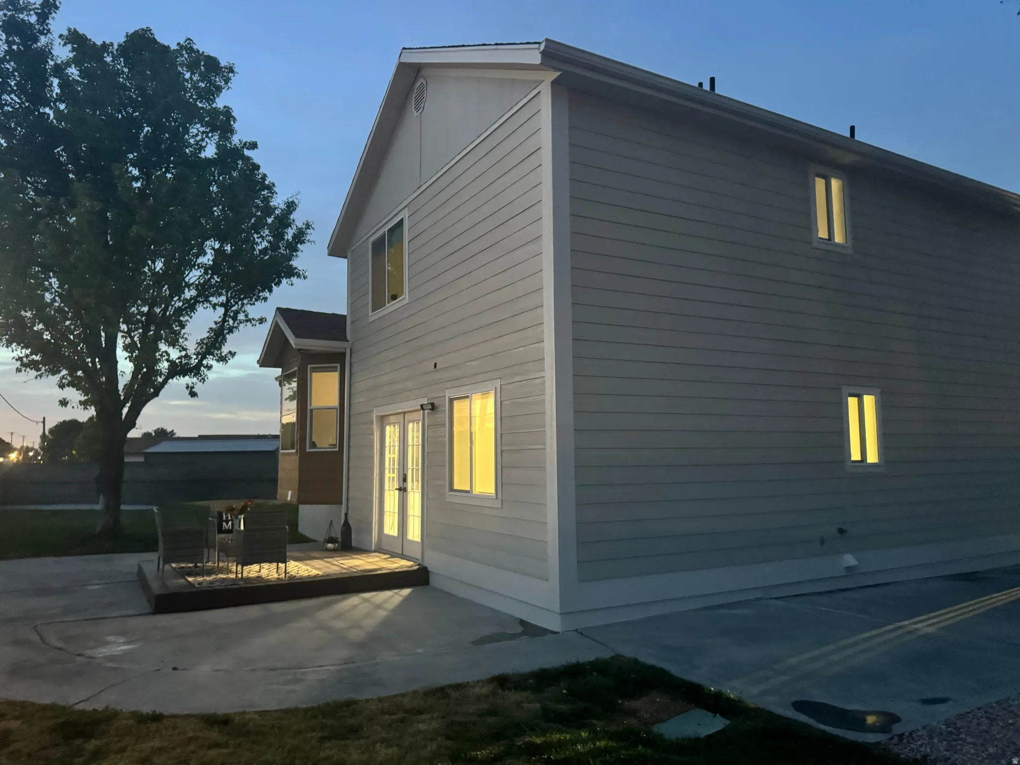 Light-toned siding exterior featuring a wooden deck, a concrete patio, and a prominent bay window