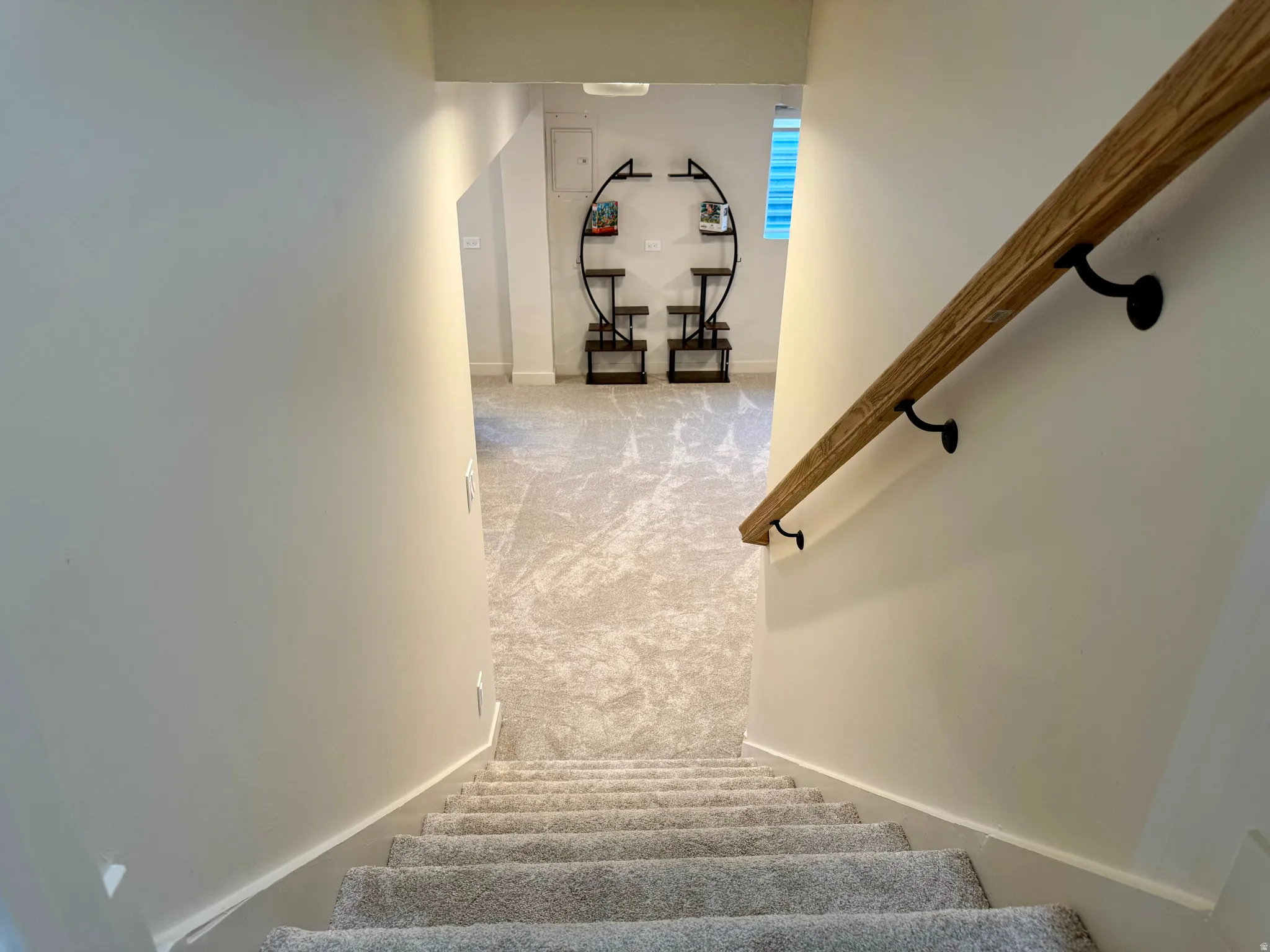 Carpeted staircase descending to a lower level featuring light-toned flooring