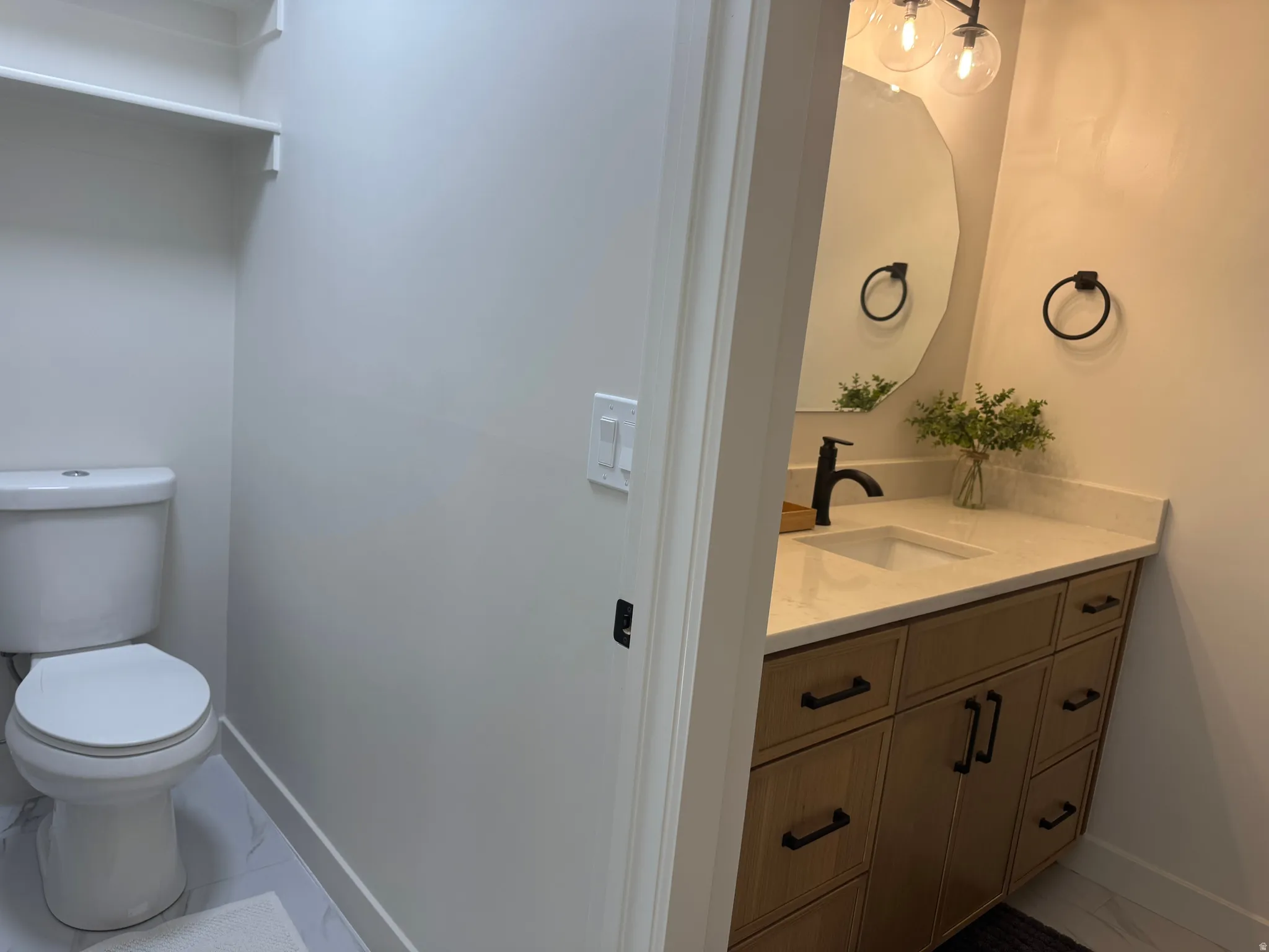 Bathroom featuring a single vanity with wood-finish cabinetry, a light-toned countertop, and an integrated rectangular sink