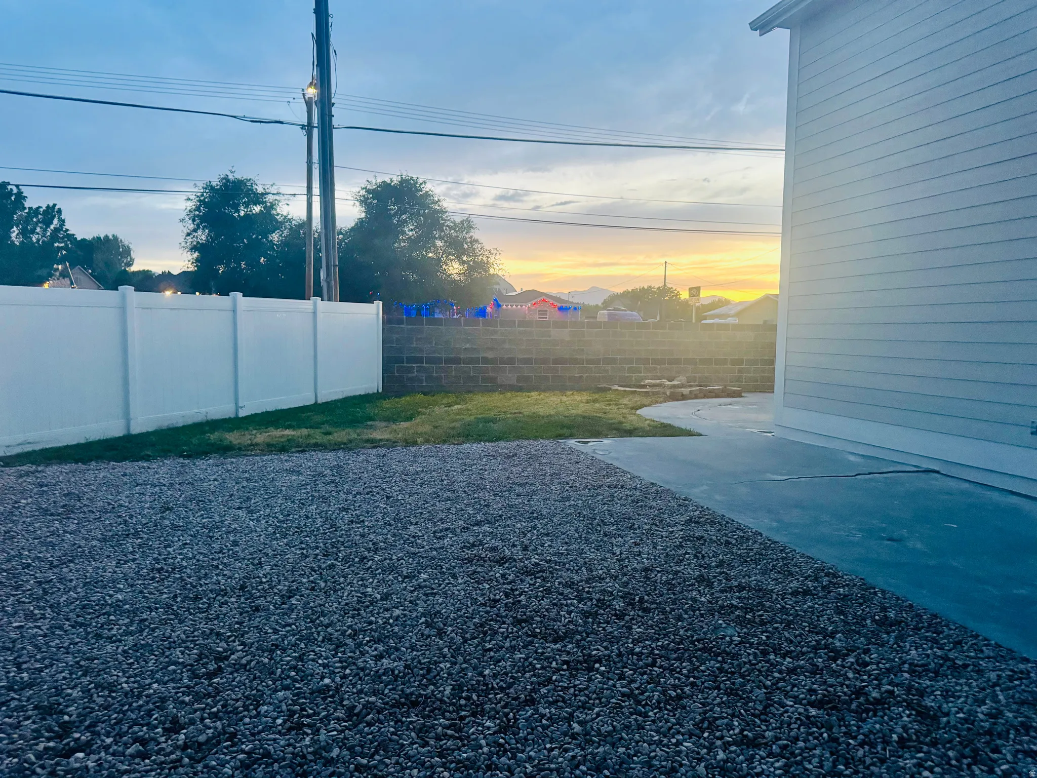 Side yard featuring a gravel area, concrete patio, and small grass patch