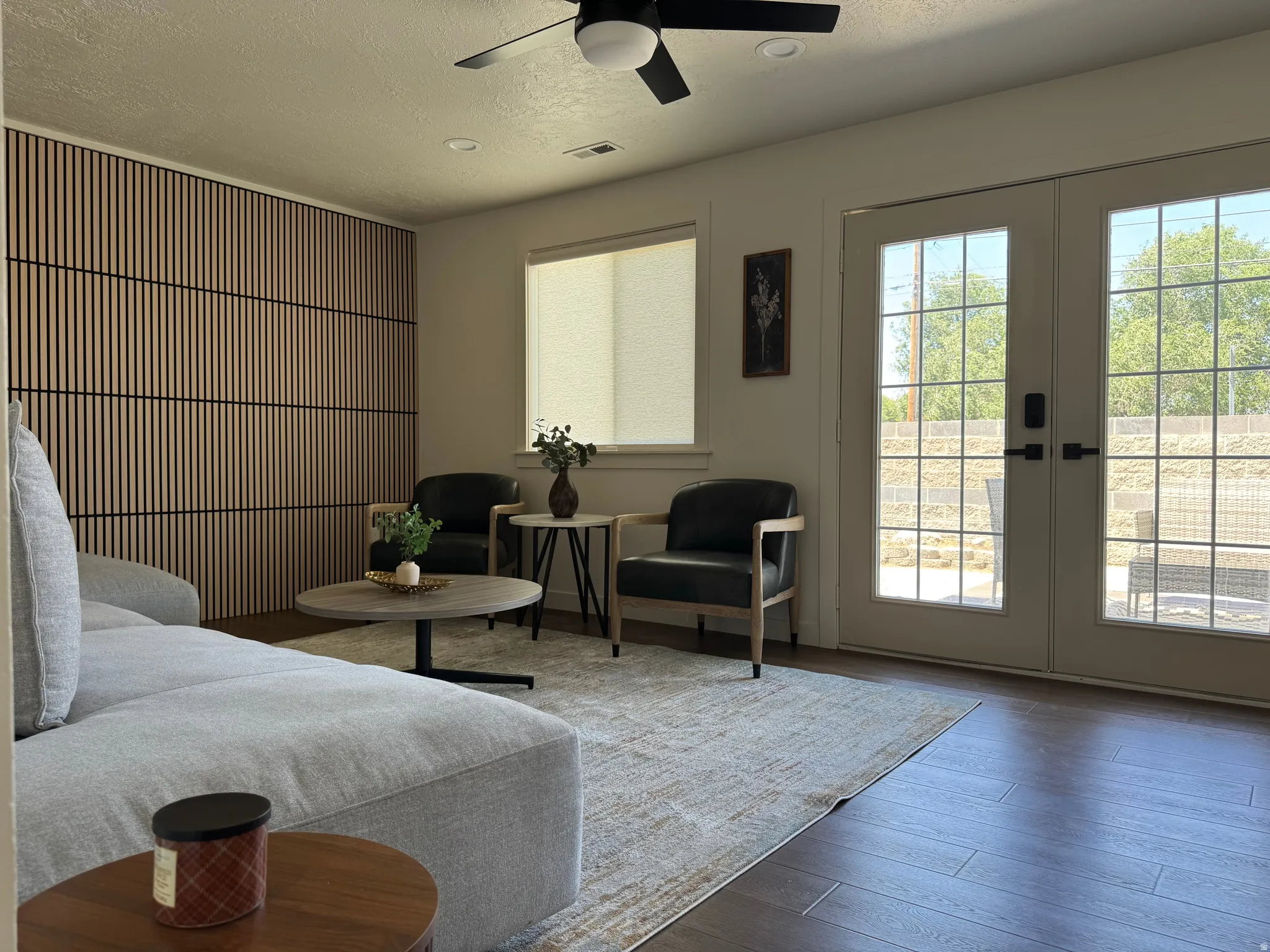 Living area featuring a slat wood accent wall, wood-finish flooring, and French doors