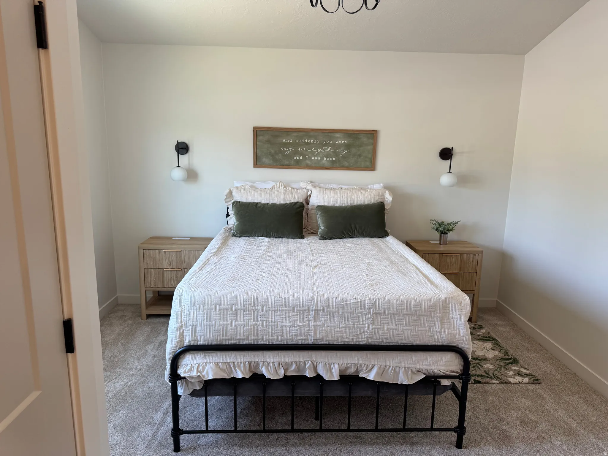 Spacious room featuring neutral wall tones, patterned carpeting, and modern black sconce lighting