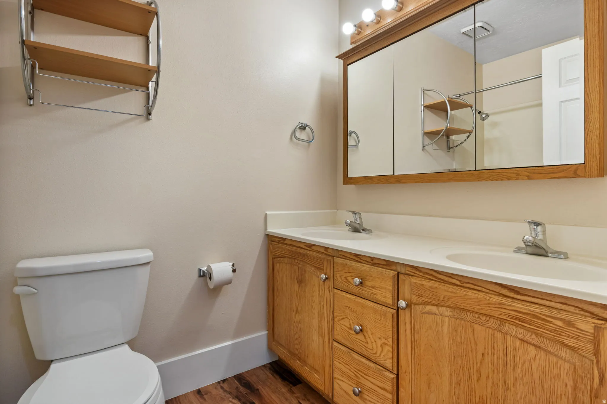 Bathroom featuring a dual vanity with light wood cabinetry, white countertops, and integrated sinks