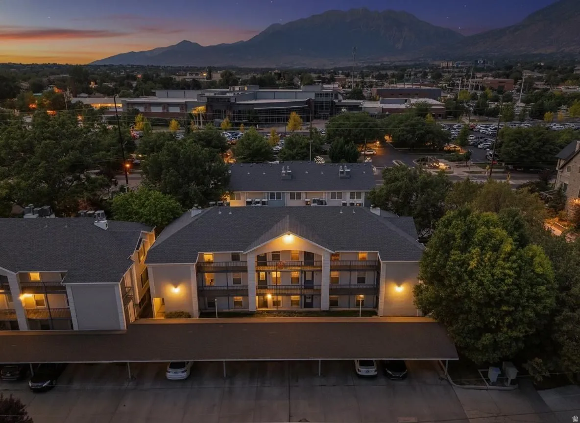 Multi-story residential building featuring covered parking, private balconies, and exterior lighting