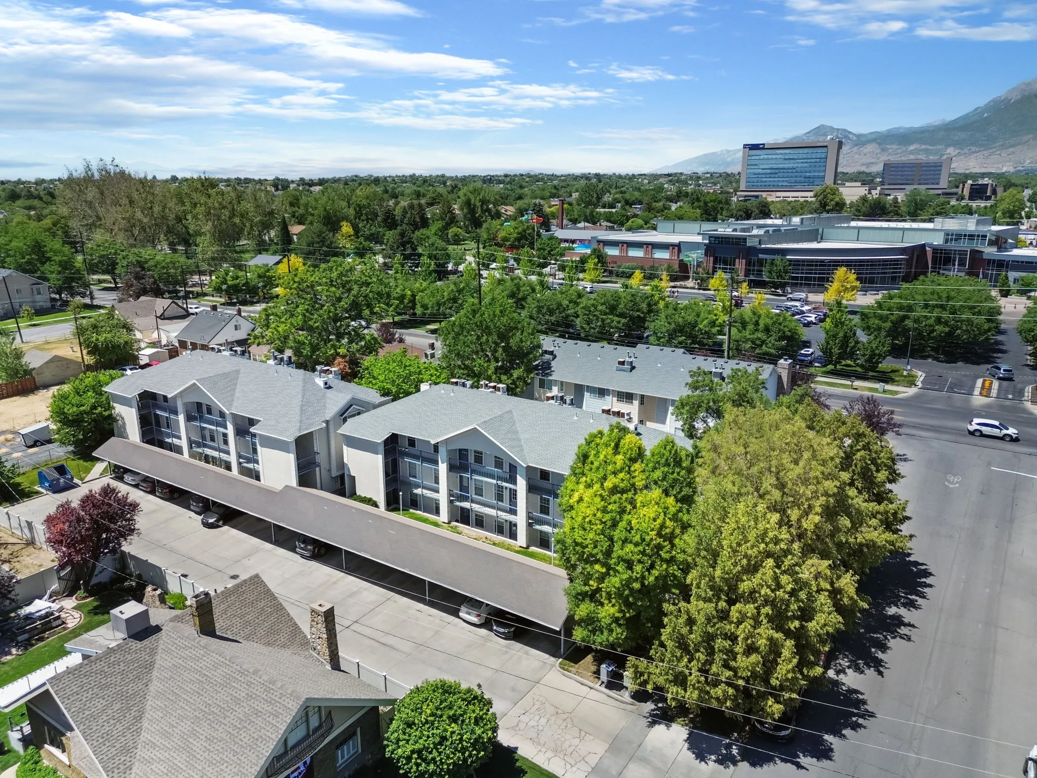 Multi-level residential buildings featuring covered parking and surrounding mature trees