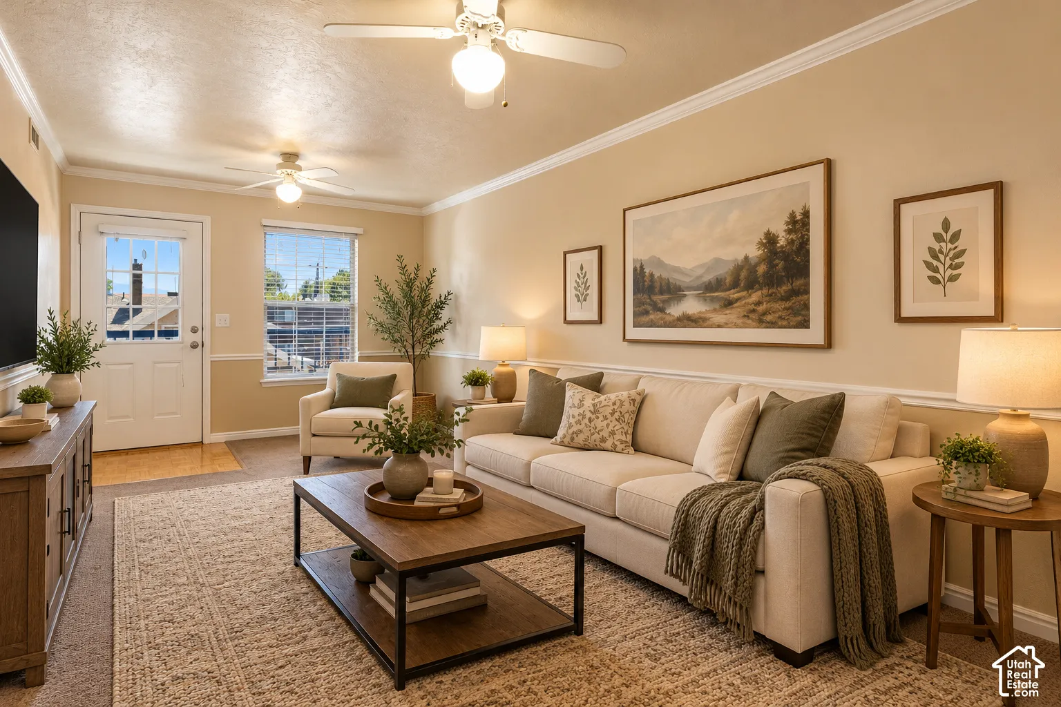 Living room featuring crown molding, chair rail trim, dual ceiling fans, and a glass-paneled exterior door
