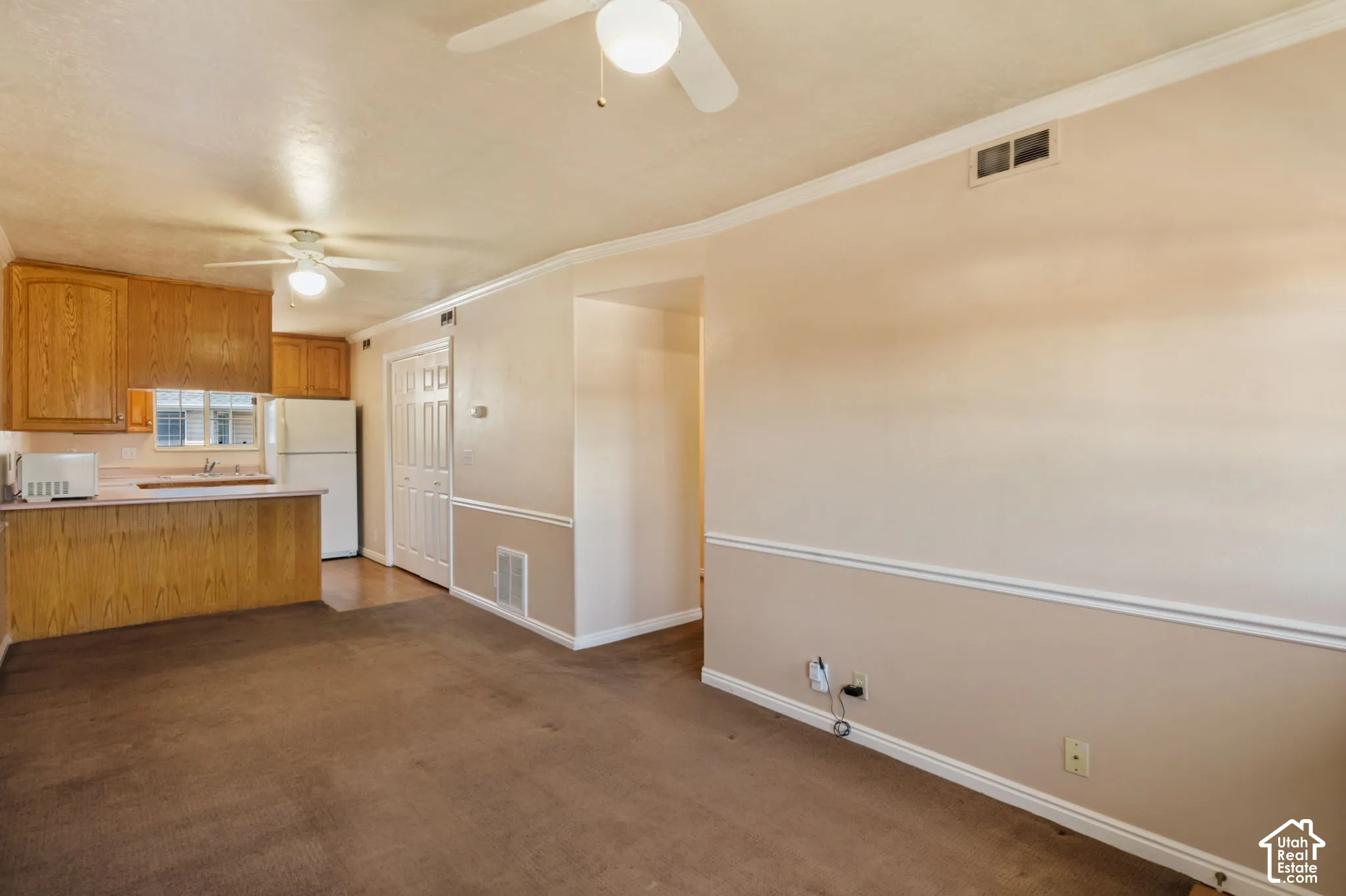 Combined living and kitchen area featuring wood cabinetry, a breakfast bar, and ceiling fans