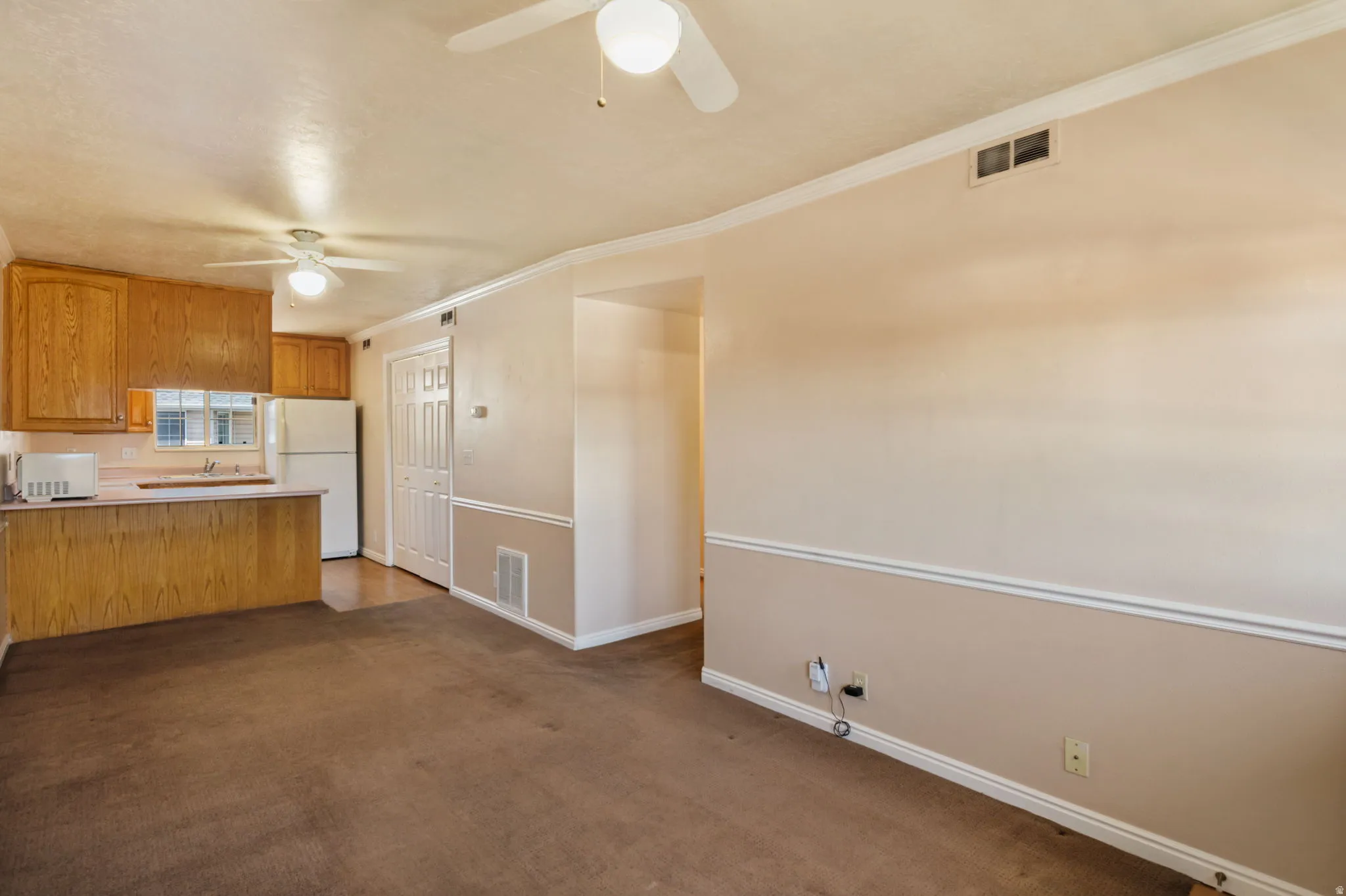 Combined living and kitchen area featuring wood cabinetry, a breakfast bar, and ceiling fans