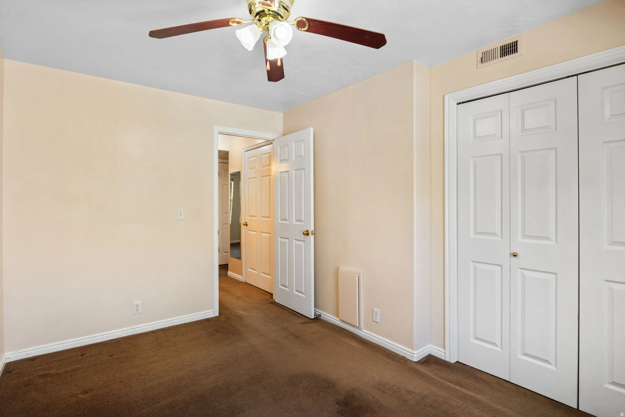 Carpeted room featuring a ceiling fan with integrated lighting, bi-fold closet doors, and white baseboards