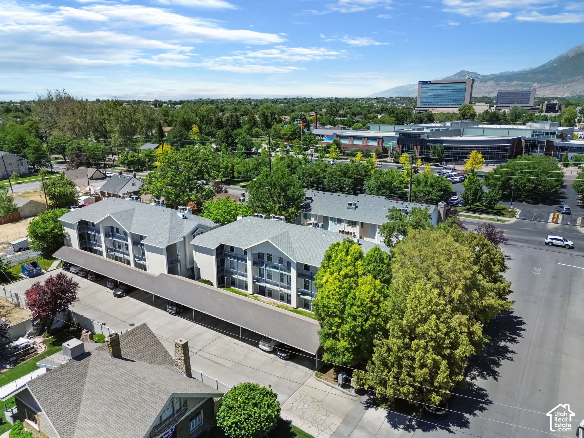Multi-level residential buildings featuring covered parking and surrounding mature trees