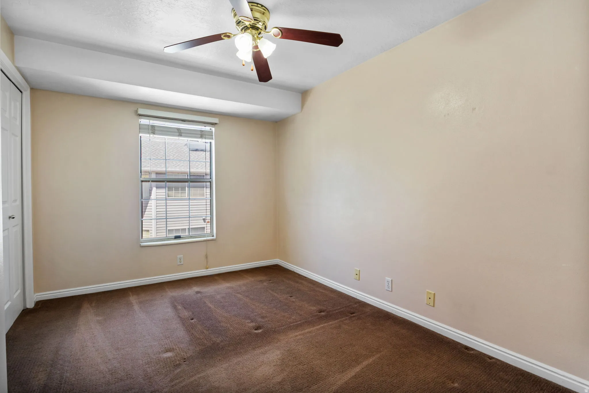 Room featuring wall-to-wall carpeting, neutral wall finishes, a window with horizontal blinds, and a ceiling fan with light fixture