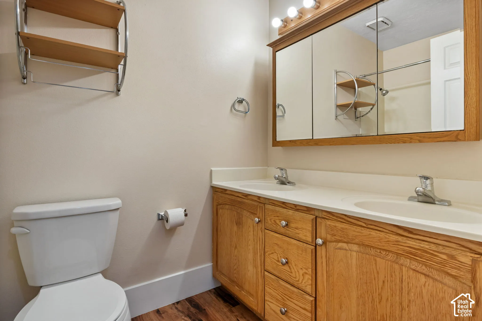 Bathroom featuring a dual vanity with light wood cabinetry, white countertops, and integrated sinks