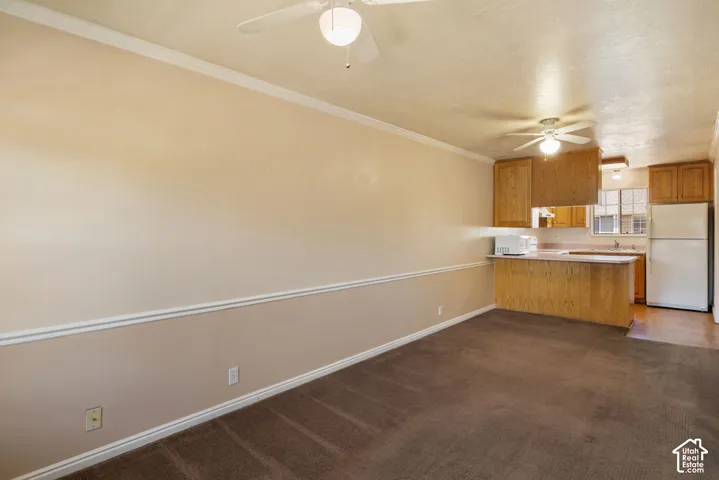 Open-concept living area featuring a kitchen with light wood cabinetry, white appliances, and a breakfast bar