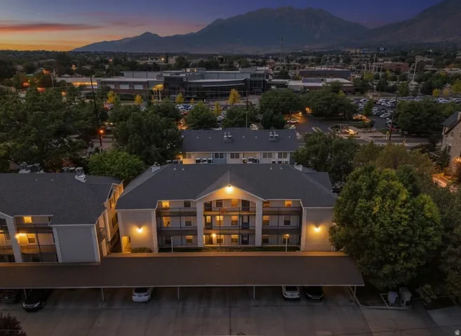 Multi-story residential building featuring covered parking, private balconies, and exterior lighting