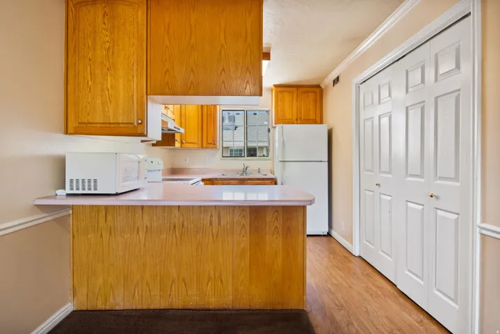 Kitchen area featuring light wood-finish cabinetry, a built-in kitchen hood, and a light-toned countertop