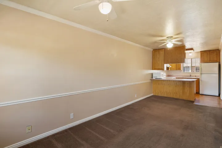 Open-concept living area featuring a kitchen with light wood cabinetry, white appliances, and a breakfast bar