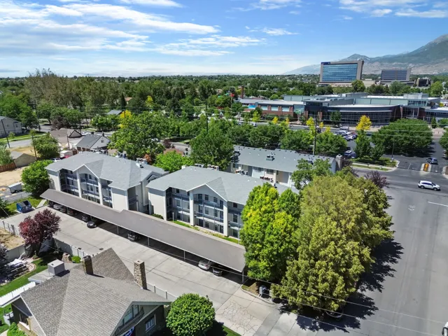 Multi-level residential buildings featuring covered parking and surrounding mature trees