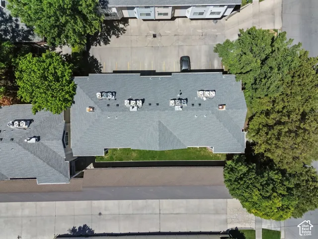 Building with a gray shingle roof, multiple rooftop HVAC units, and surrounding paved parking areas