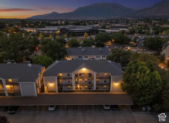 Multi-story residential building featuring covered parking, private balconies, and exterior lighting