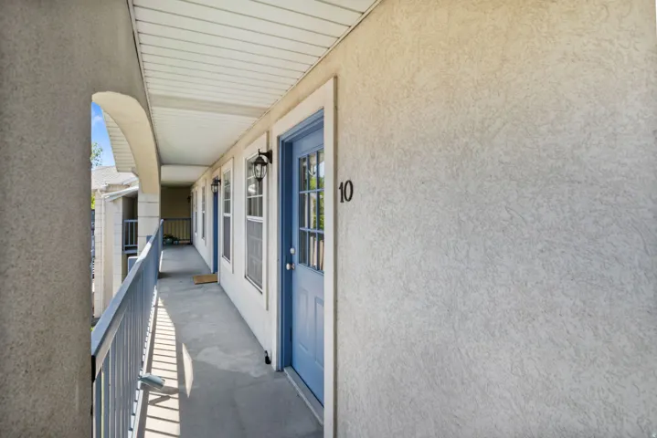 Covered exterior walkway featuring a protective railing and textured wall finish