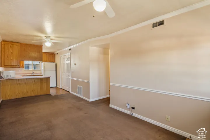 Combined living and kitchen area featuring wood cabinetry, a breakfast bar, and ceiling fans