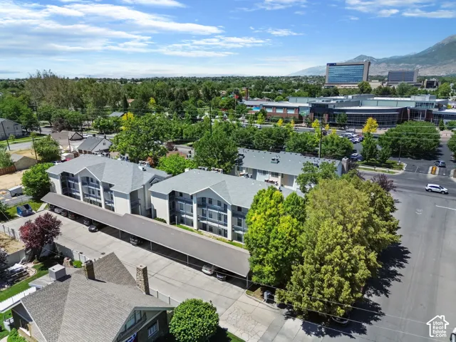 Multi-level residential buildings featuring covered parking and surrounding mature trees